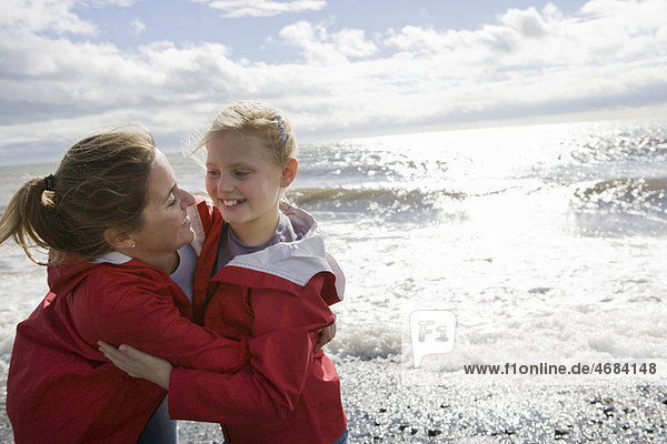 Mother and daughter hugging at beach