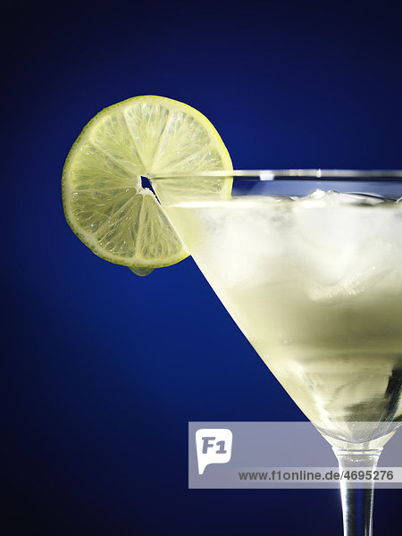 Eisgekühlter Cocktail in einem Martini-Glas mit Limettenscheibe garniert