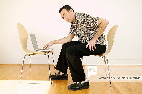 Man using laptop in bare room