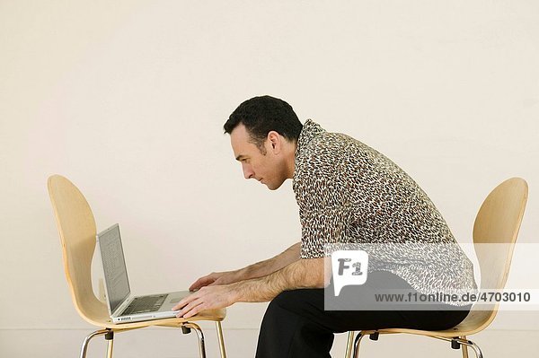 Man using laptop in bare room