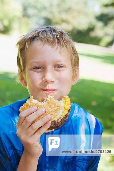 Portrait of boy eating hamburger outside