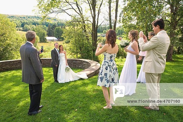 Group of people photographing a newlywed couple in a park  East Meredith  New York State  USA