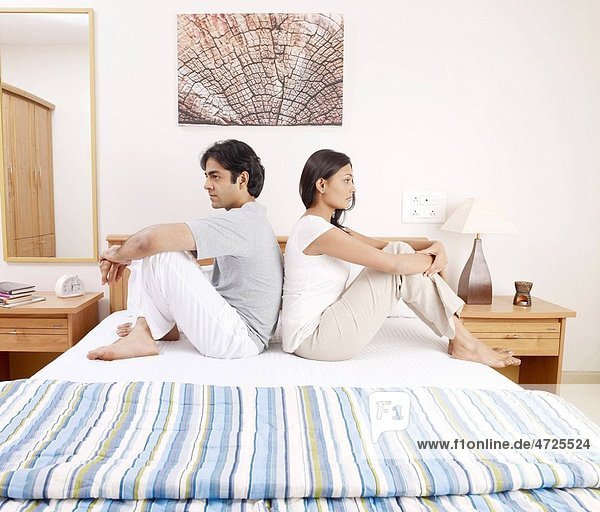Young man woman sitting back to back on bed MR702V 702U