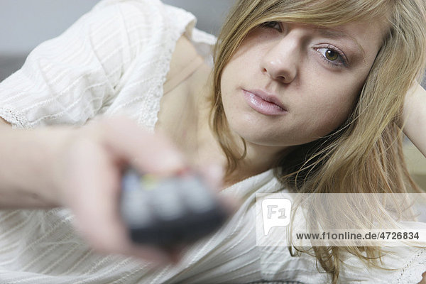 Young woman lying down with remote in her hand