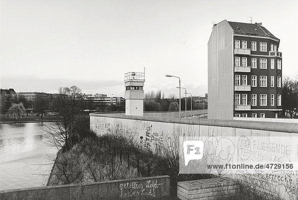 Blick über die Berliner Mauer 1985  allein stehendes Wohnhaus neben Wachturm angrenzend an den Todesstreifen  Berlin  Deutschland  Europa