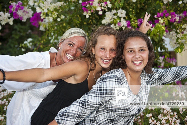 Porträt einer Mutter mit zwei dreizehnjährigen Mädchen  hinten Blumen