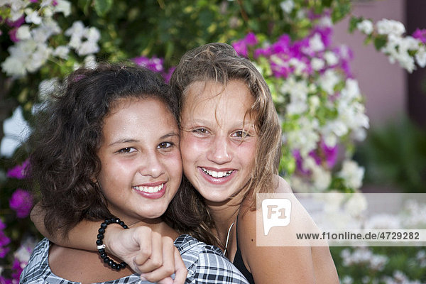 Portrait of two thirteen-year-olds girls in front of flowers