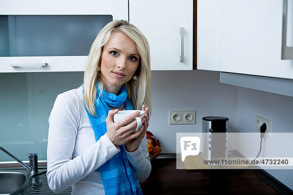 Eine junge Frau mit Teetasse in der Küche