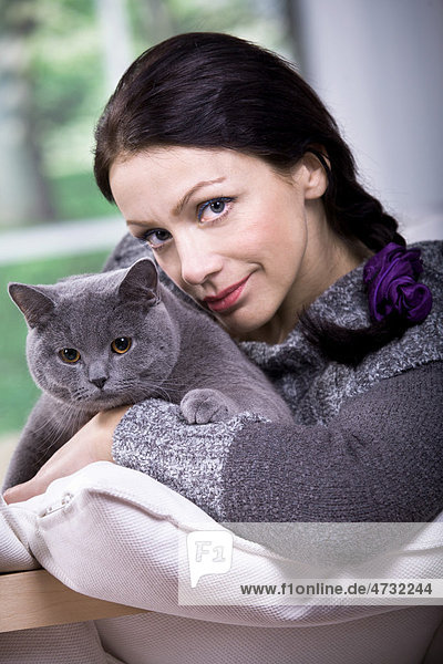 Junge Frau zu Hause mit einer Britischen Kurzhaar-Katze