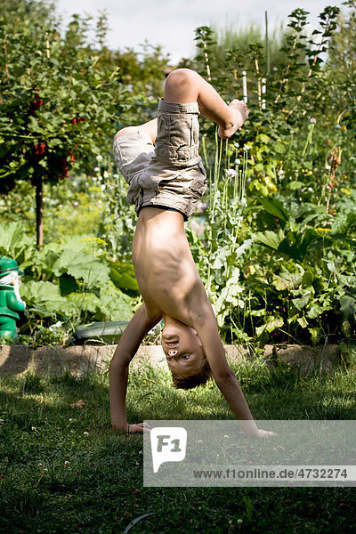 Young boy doing a handstand in the garden