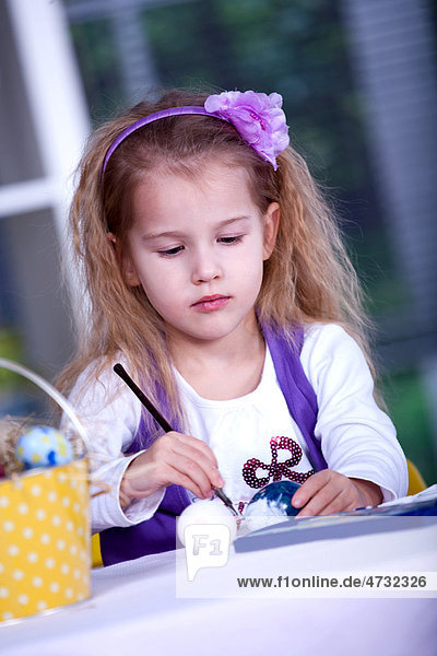 Little girl painting Easter eggs