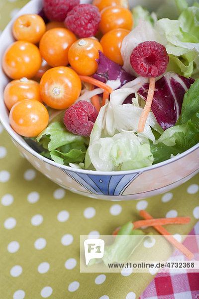 Salad with Physalis or Cape Gooseberry and raspberries in a bowl
