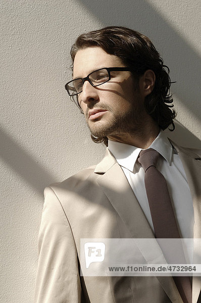 Modeaufnahme eines Mannes mit Brille und Anzug im Sonnenlicht