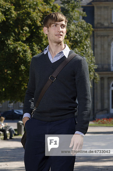 Junger Mann in eleganter Kleidung mit Tasche vor dem Neuen Schloss in Stuttgart  Baden-Württemberg  Deutschland  Europa