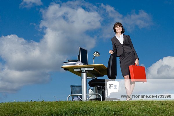 Geschäftsfrau mit red Aktenkoffer am Schalter auf Rasen