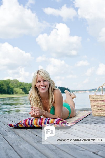 Portrait of woman sunbathing by lake