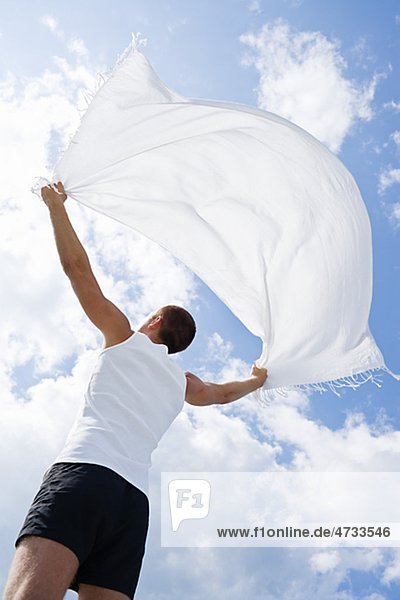 Man holding white blanket in wind