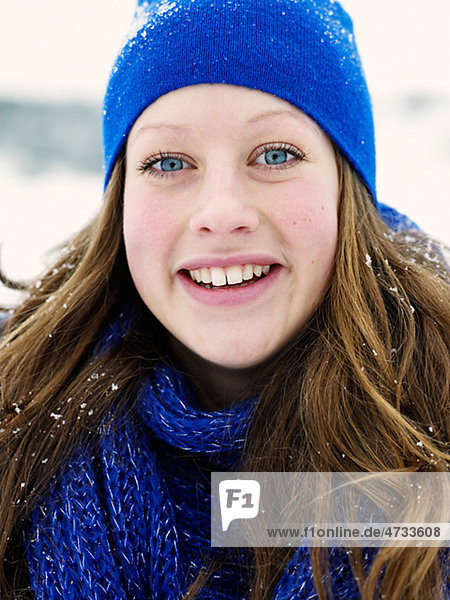 Portrait of young woman wearing blue hat and blue wooly scarf
