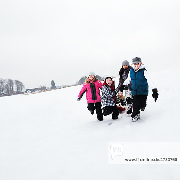 Children tobogganing on snow slope