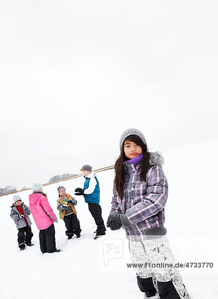 Portrait of girl with friends playing in snow