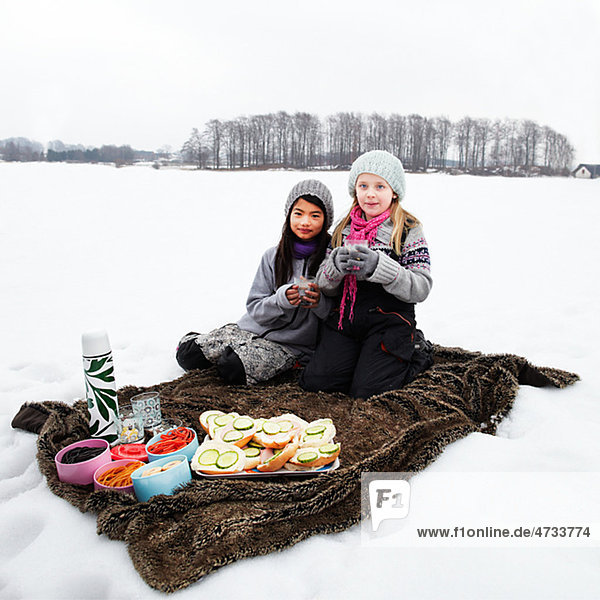 Portrait of two girls having picnic in snow