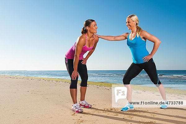 Two women exercising together on beach