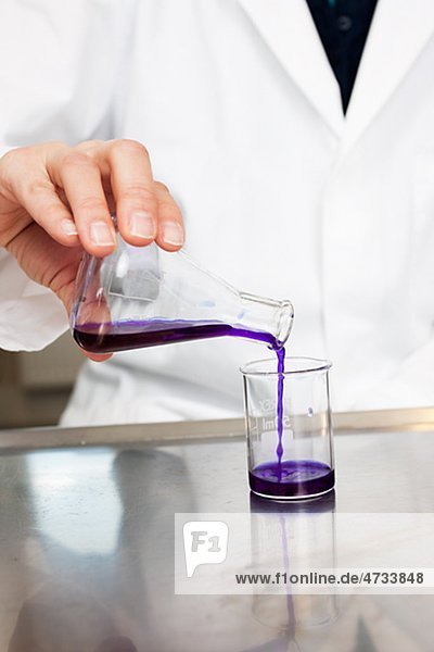Wissenschaftler strömenden Flüssigkeit aus Becherglas