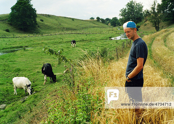 Landwirt stehend auf Feld mit Kühe im Hintergrund