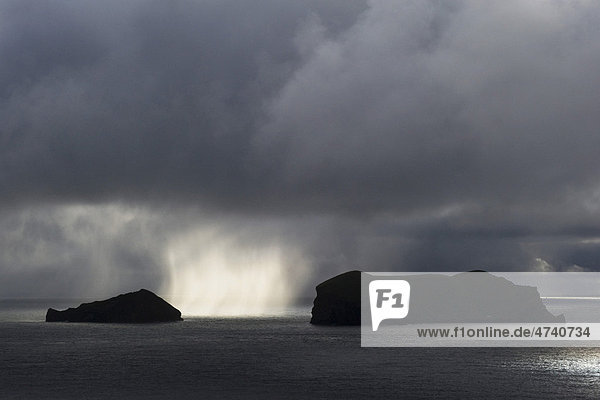 Sonnendurchleuchteter Regenschauer zwischen zwei Westmännerinseln oder Vestmannaeyjar  Südisland  Island  Europa