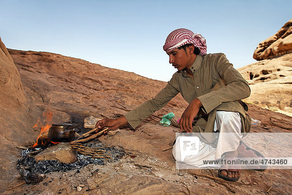 Young Bedouin stoking a campfire in the desert  Wadi Rum  Hashemite Kingdom of Jordan  Middle East  Asia