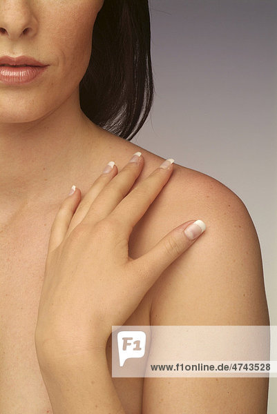 Young woman touching her shoulder with her hand