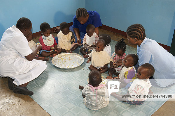 Kleinkinder und Kinderkrankenschwestern beim Essen in einem Waisenhaus in der Nähe von Bukoba Tansania Afrika