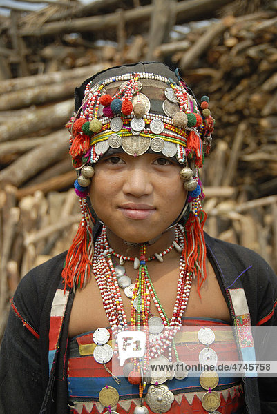 Portrait  Mädchen der Akha Eupa Ethnie lächelt  traditionelle Kleidung  Haube als Kopfbedeckung mit bunten Bommeln Ketten und Silbermünzen  Ban Yangpa  Distrikt Samphan  Provinz Phongsaly  Phongsali  Laos  Südostasien  Asien