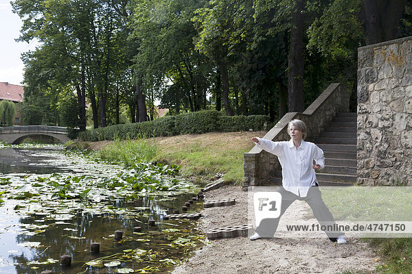Anna Elisa Heine demonstrating a Qi Gong exercise  Nei Yang Gong  Internal Qi Gong Cultivation course in Lindenhof  Lindenhof-pond with water lilies and bridges  Schoeneberg  Berlin  Germany  Europe
