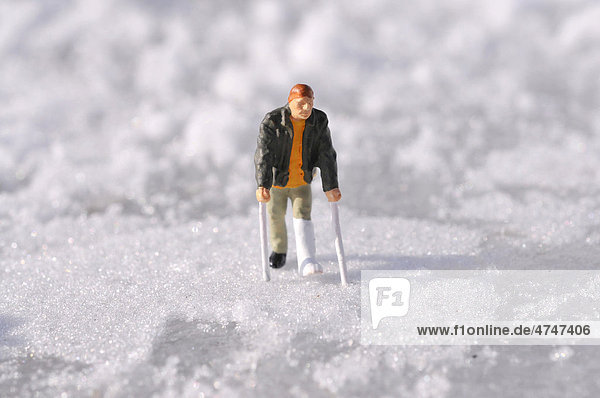 Figur mit Gipsbein im Schnee