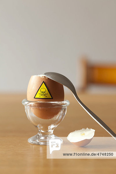 Hühnerei mit Totenkopf-Warnzeichen in einem Eierbecher