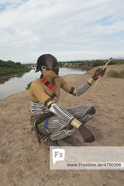 Karo Mann mit Körperbemalung und Gesichtsbemalung sitzt auf seiner Kopfstütze  Omo-Tal  Südäthiopien  Äthiopien  Afrika