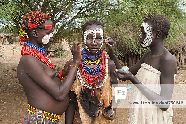 Drei junge Karo Frauen beim Auftragen von Make-up  Gesichtsbemalung  Omo-Tal  Südäthiopien  Äthiopien  Afrika