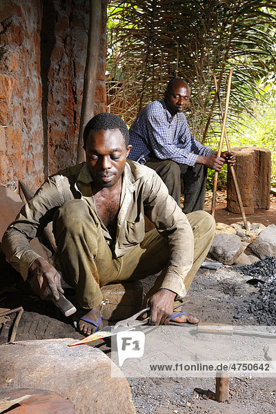 Smith making a musical instrument from scrap metal  and another man operating bellows  Babungo  Cameroon  Africa