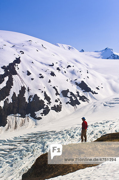 Männlich Wanderer übersieht Exit Gletscher und Harding Icefield die von einem Felsvorsprung auf Harding Icefield Trail  Kenai Fjords National Park  Kenai-Halbinsel  Südalaska  Frühling