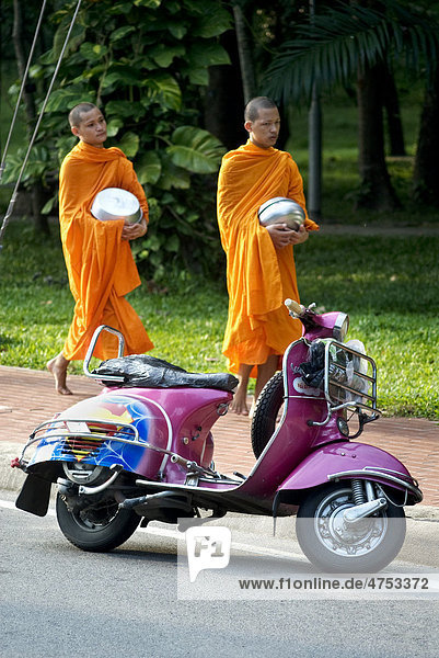 Buddhist monks collecting alms in the early morning and a Vespa scooter in Chiang Mai  Thailand  Asia
