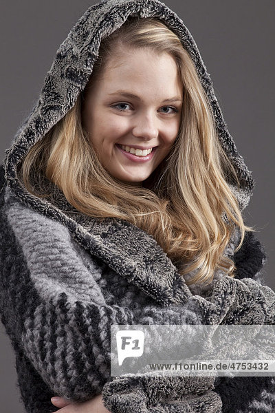 Lächelnde junge Frau im winterlichen Kapuzenmantel