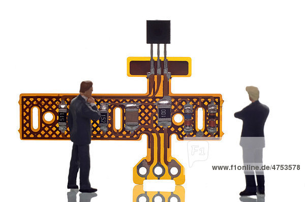 Zwei Businessmann Figuren stehen rätselnd vor einem elekronischen Bauteil  Symbolbild Analyse  Problemlösung  Elektronik