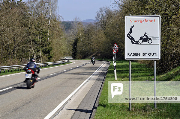 Motorradfahrer auf einer Landstraße mit Warnhinweis  Schild  Sturzgefahr  Rasen ist out  Eifel  Rheinland-Pfalz  Deutschland  Europa