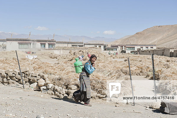 Frau trägt Kanister auf dem Rücken  Ernte von Gerste  Dorf Lungchang bei Old Tingri  Mount Everest-Gebiet  Himalaja  Zentraltibet  Ü-Tsang  Autonomes Gebiet Tibet  Volksrepublik China  Asien