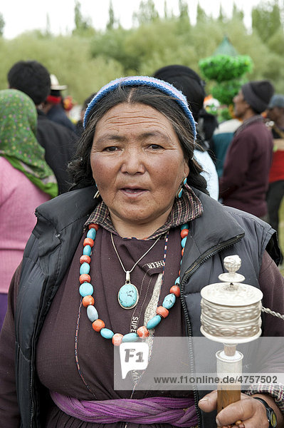 Tibetisches Fest  Portrait  alte Frau in Tracht gekleidet dreht Gebetsmühle  Halskette aus Edelsteinen  Leh  Distrikt Ladakh  Bundesstaat Jammu und Kaschmir  Indien  Südasien  Asien