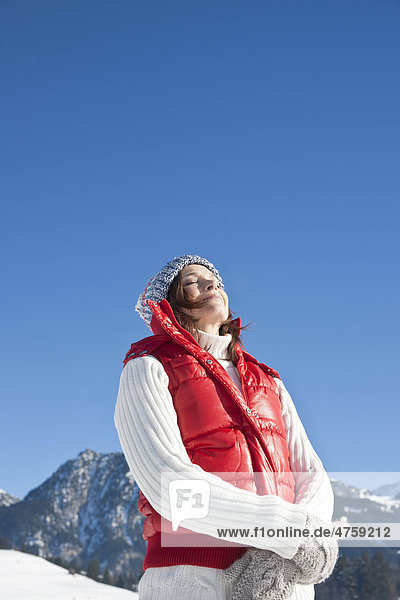 Frau steht mit geschlossenen Augen in Winterlandschaft  Tannheimer Tal  Tirol  Österreich