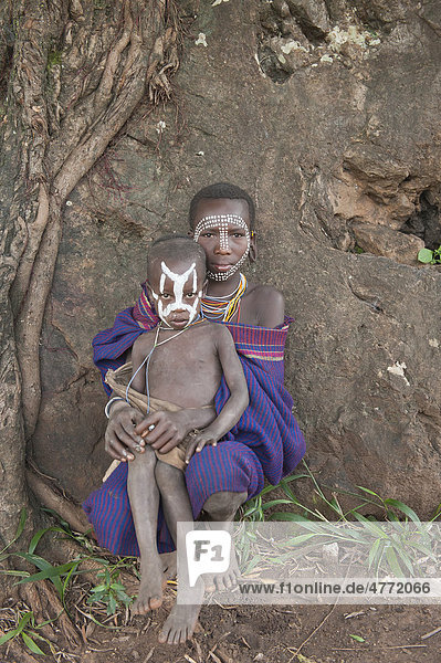 Bemalte Gesichter einer jungen Surma Frau mit ihrem Kind vor einem Baum  Kibish  Omo-Tal  Äthiopien  Afrika