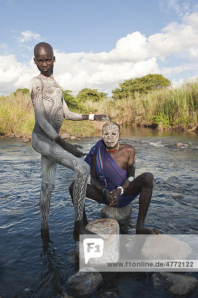 Zwei Surma Männer mit Gesichtsbemalung und Körperbemalung im Wasser  Kibish  Omo-Tal  Äthiopien  Afrika