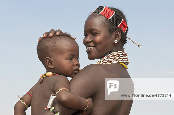 Junge Hamar Frau mit Halskette aus Kaurimuscheln und bunten Plastikperlen hält ihr Baby im Arm  Omo-Tal  Süd Äthiopien  Afrika